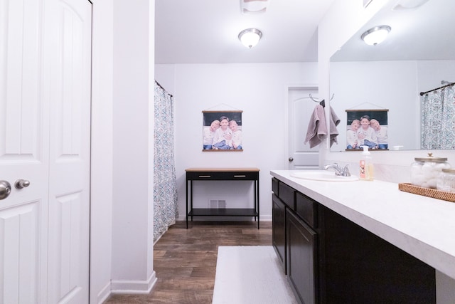 full bathroom featuring baseboards, wood finished floors, and vanity