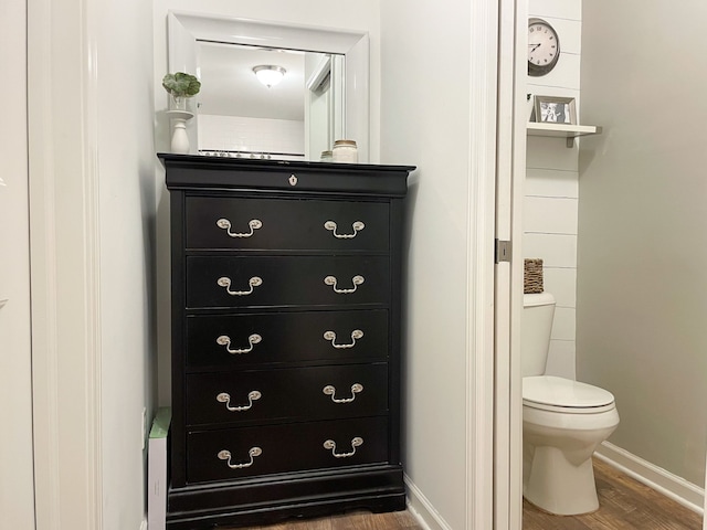 bathroom featuring baseboards, wood finished floors, and toilet