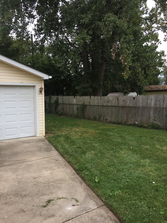 view of yard with a garage, fence, and concrete driveway