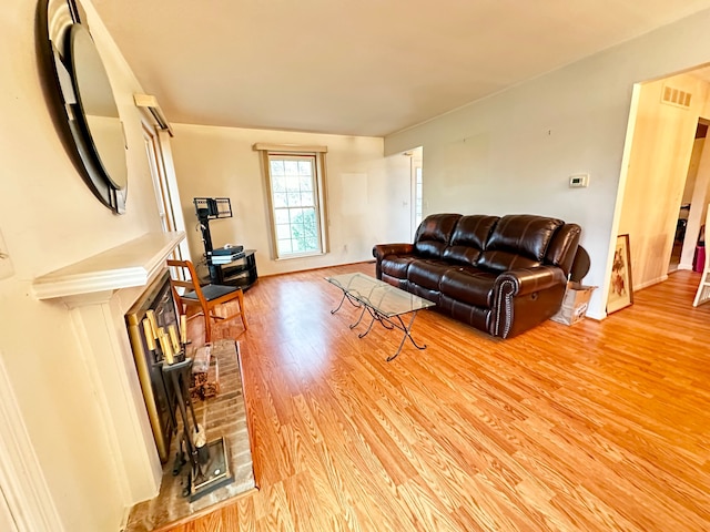 living area with light wood-style floors, baseboards, visible vents, and a fireplace