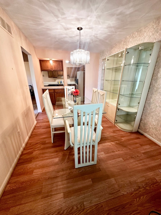 dining room with baseboards, an inviting chandelier, wood finished floors, and visible vents
