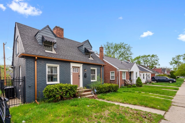 19165 Rutherford St, Detroit, MI 48235 - new england style home featuring roof with shingles, fence, brick siding, a front lawn, and a chimney