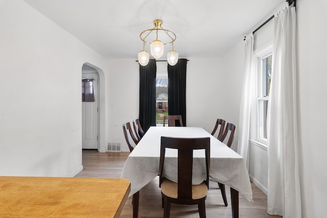 19165 Rutherford St, Detroit, MI 48235 - dining space with arched walkways, light wood-style floors, visible vents, and baseboards