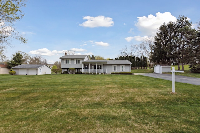 tri-level home with an outdoor structure, a front lawn, a storage shed, and a detached garage