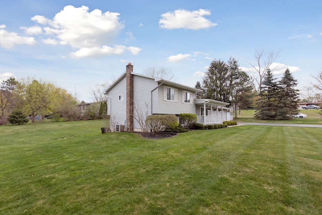view of home's exterior with a lawn, central air condition unit, a chimney, and a porch