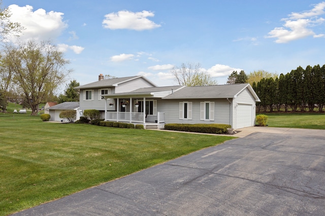 tri-level home featuring a chimney, a front lawn, a porch, and driveway
