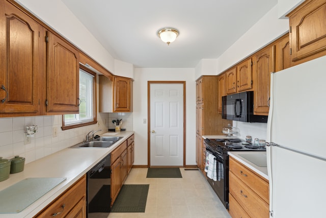 kitchen featuring light countertops, a sink, black appliances, and tasteful backsplash