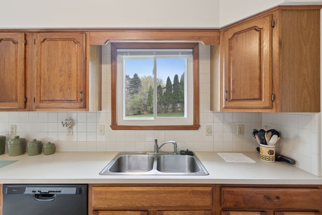 kitchen with a sink, light countertops, black dishwasher, and brown cabinets