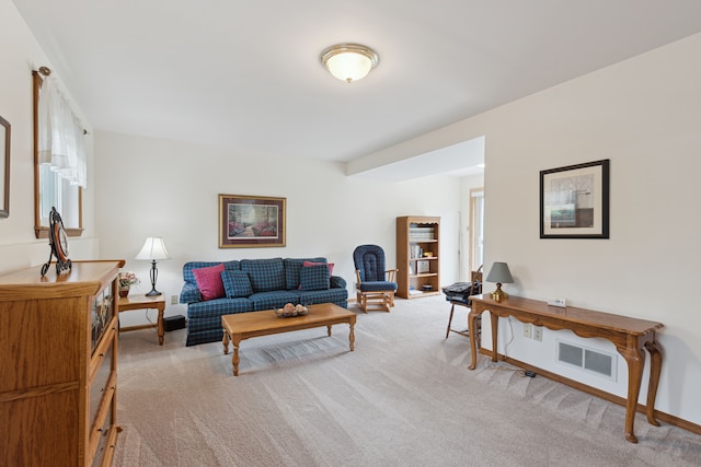 living area with visible vents, baseboards, and light carpet