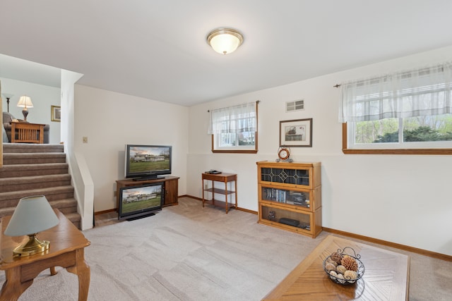 living room featuring baseboards, visible vents, light carpet, and stairway