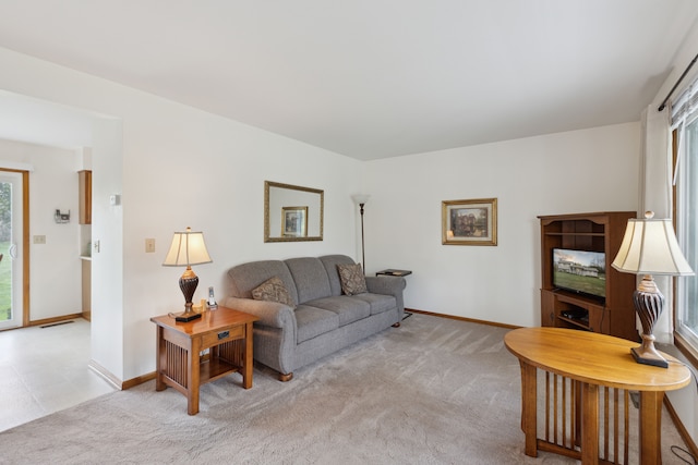 living room featuring baseboards, light colored carpet, and visible vents