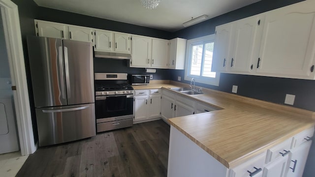 kitchen with under cabinet range hood, white cabinetry, appliances with stainless steel finishes, and a sink