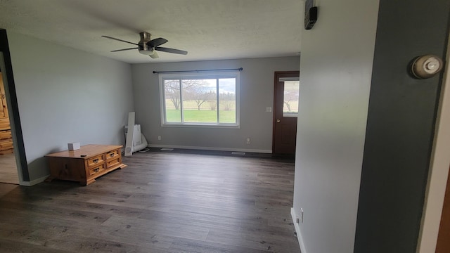 spare room featuring radiator, baseboards, a ceiling fan, and dark wood finished floors