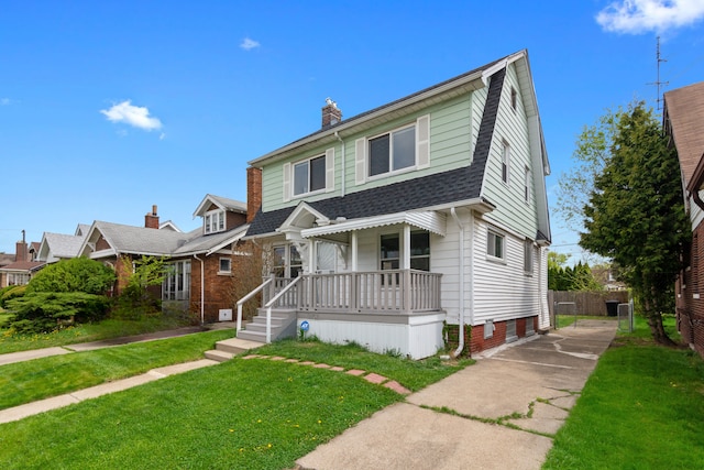 view of front of property featuring covered porch, roof with shingles, a chimney, and a front yard
