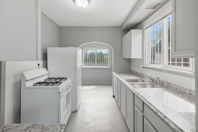 kitchen with a wealth of natural light, white appliances, light countertops, and a sink