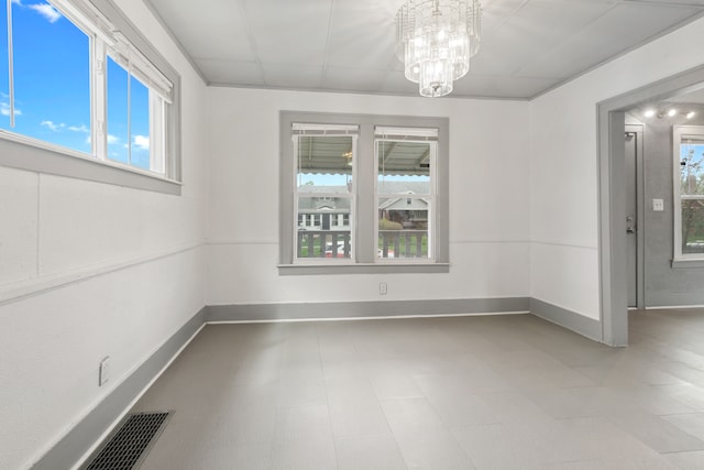 unfurnished dining area with baseboards, a healthy amount of sunlight, and an inviting chandelier
