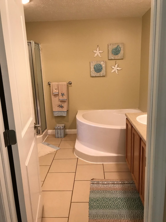full bath featuring tile patterned flooring, vanity, a textured ceiling, a bath, and a stall shower