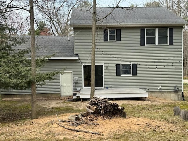 rear view of house with a deck and roof with shingles