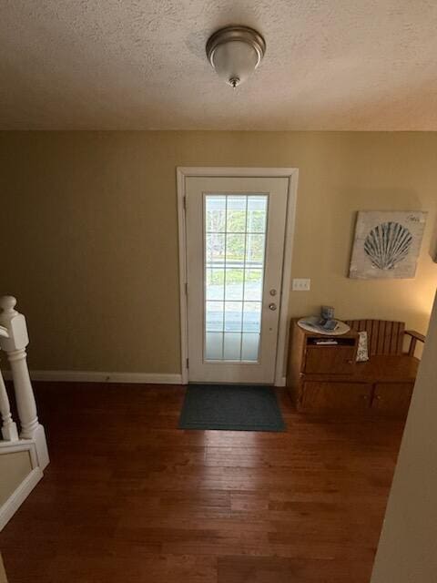 entryway with a textured ceiling, baseboards, and wood finished floors