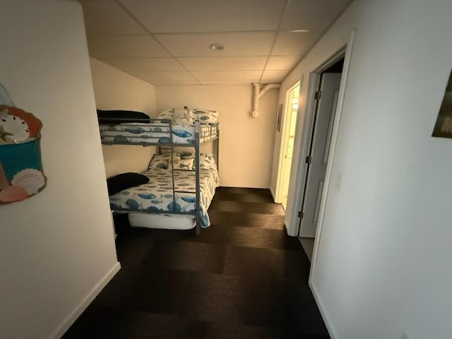 hall featuring baseboards and a drop ceiling