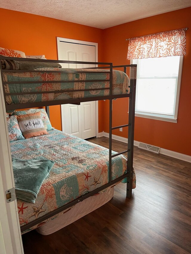 bedroom featuring baseboards, wood finished floors, and visible vents