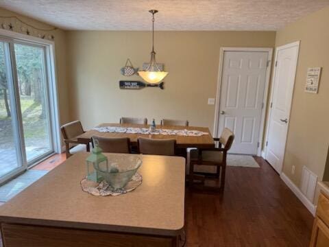 dining area with baseboards, dark wood-style flooring, and a textured ceiling