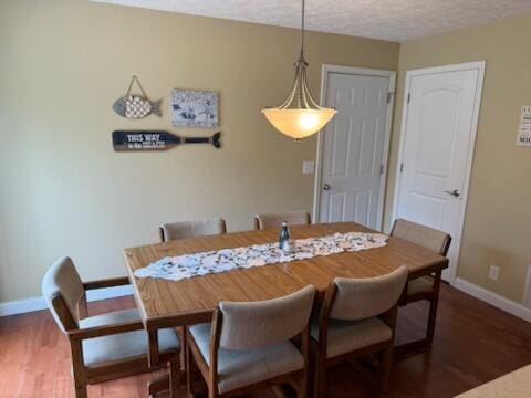 dining room with a textured ceiling, baseboards, and wood finished floors