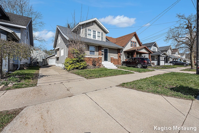 bungalow-style home with a residential view, roof with shingles, and a front yard