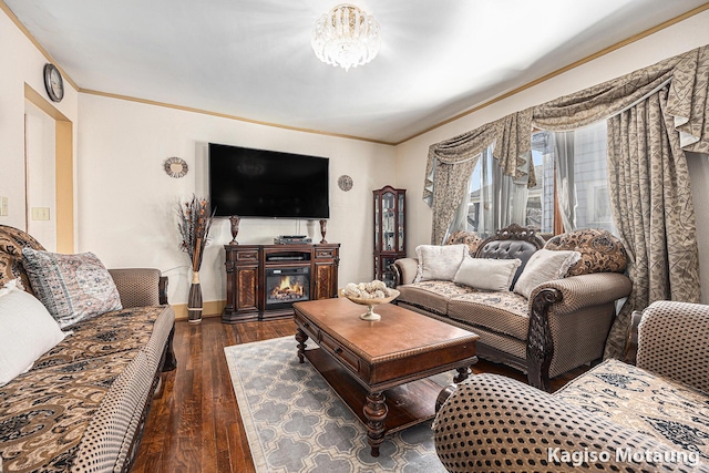 living area featuring a glass covered fireplace, baseboards, ornamental molding, and dark wood-type flooring