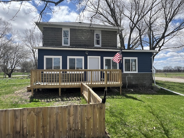 rear view of property with a wooden deck, a yard, and fence