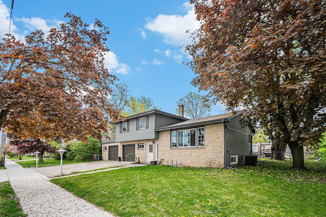 604 E N St, Owosso, MI 48867 - tri-level home with a garage, brick siding, concrete driveway, and central AC unit