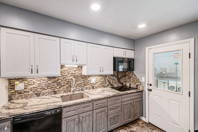 604 E N St, Owosso, MI 48867 - kitchen featuring black appliances, a sink, backsplash, light stone counters, and white cabinets