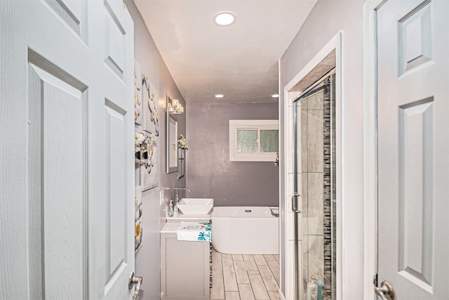 604 E N St, Owosso, MI 48867 - bathroom featuring vanity, a bath, a shower stall, wood finished floors, and recessed lighting