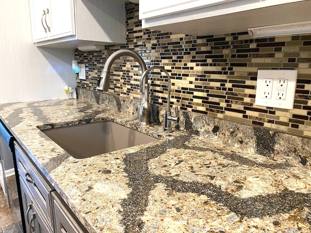 604 E N St, Owosso, MI 48867 - kitchen view of a sink, backsplash, light stone countertops, and white cabinetry