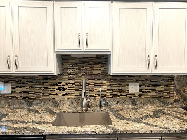 604 E N St, Owosso, MI 48867 - kitchen featuring a sink, backsplash, white cabinets, and dark stone countertops