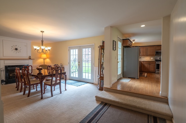 dining area with french doors, recessed lighting, light wood-style flooring, a notable chandelier, and a tile fireplace