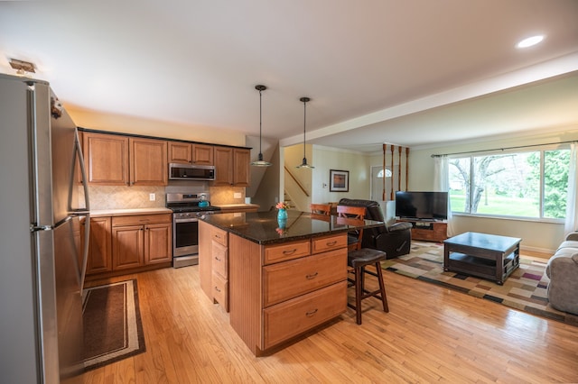 kitchen featuring a center island, a kitchen breakfast bar, open floor plan, stainless steel appliances, and light wood-type flooring