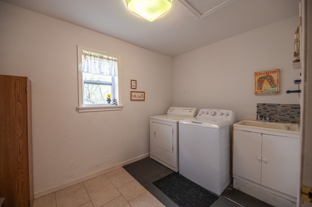 laundry area featuring washing machine and dryer, light tile patterned floors, a sink, cabinet space, and baseboards