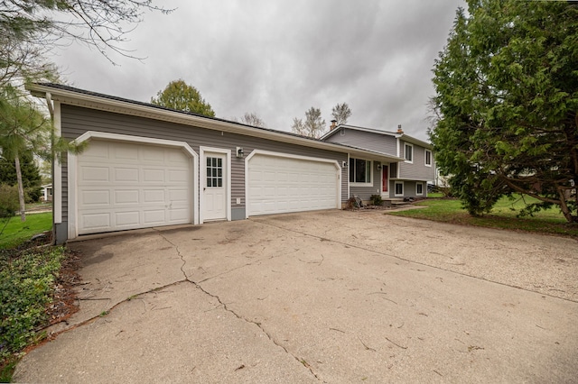 tri-level home featuring driveway, a chimney, and a garage