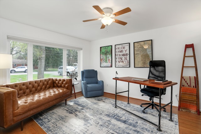 office space featuring a ceiling fan, baseboards, a healthy amount of sunlight, and wood finished floors