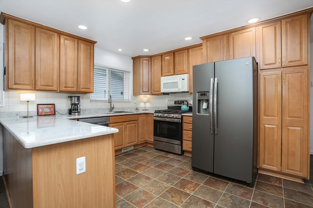 kitchen featuring stone finish flooring, appliances with stainless steel finishes, tasteful backsplash, a sink, and a peninsula