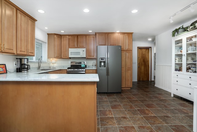 kitchen featuring a sink, stainless steel appliances, recessed lighting, a peninsula, and backsplash