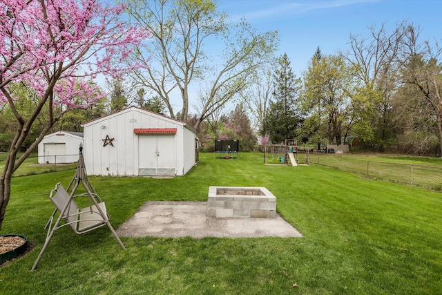 view of yard featuring fence, an outdoor structure, a playground, and an outdoor fire pit