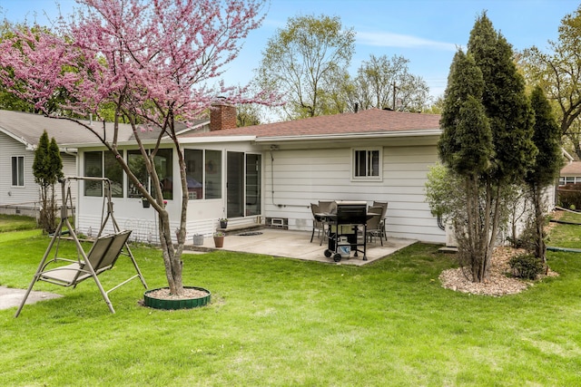 rear view of property featuring a lawn, a patio, a chimney, and a sunroom