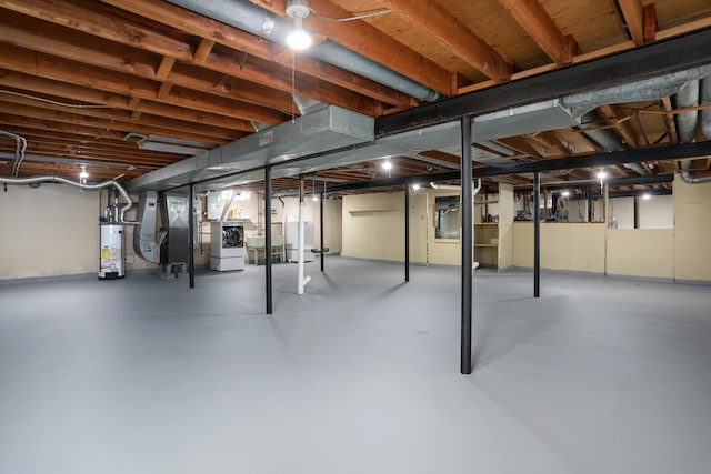 unfinished basement with washing machine and clothes dryer, heating unit, and water heater