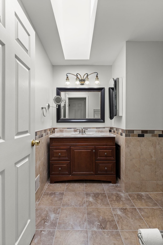 bathroom featuring tile walls, a wainscoted wall, vanity, and visible vents