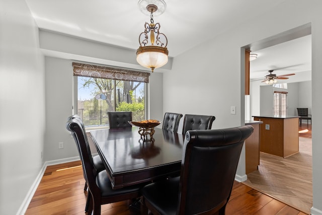 dining space featuring baseboards, a ceiling fan, and light wood-style flooring