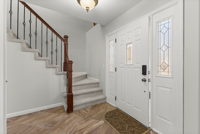 foyer entrance featuring baseboards, stairs, and plenty of natural light