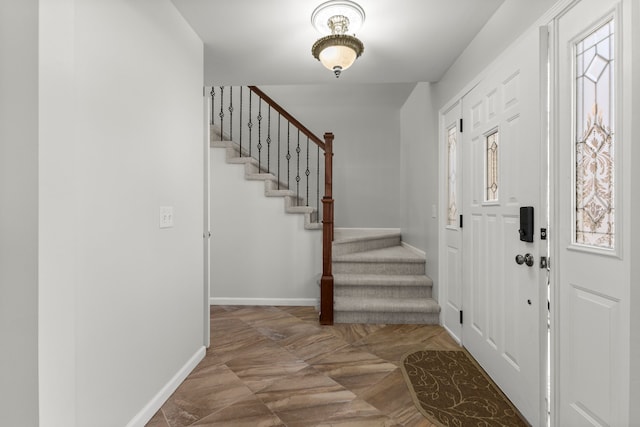 entrance foyer featuring baseboards, a wealth of natural light, and stairway