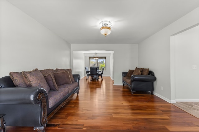 living area with baseboards, wood finished floors, and a chandelier